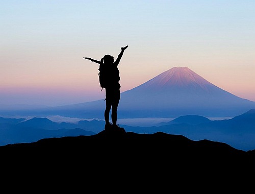 Hiker at top of mountain with arms uplifted
